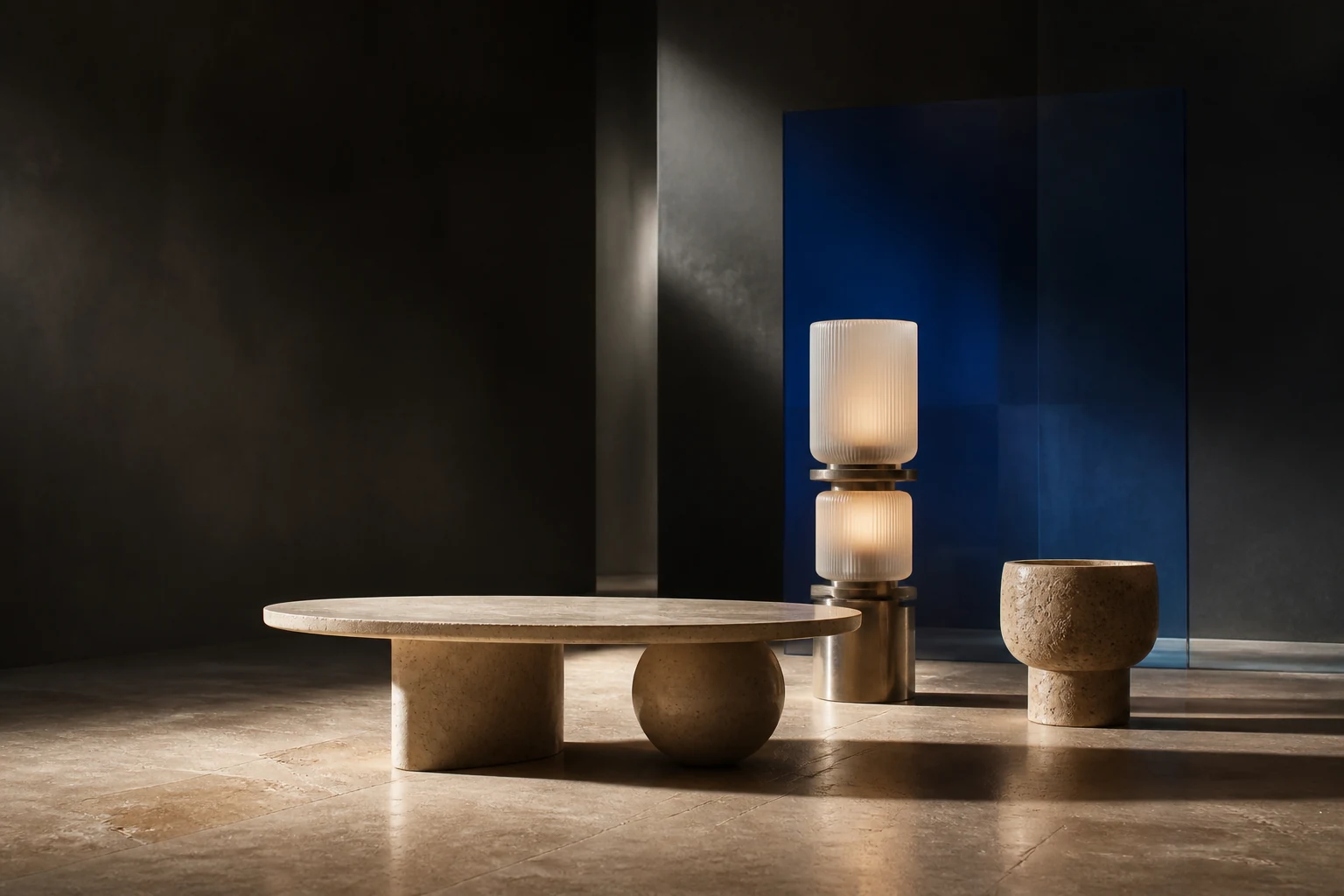 Low travertine table, stacked lamp, and stone vessel in an architectural studio