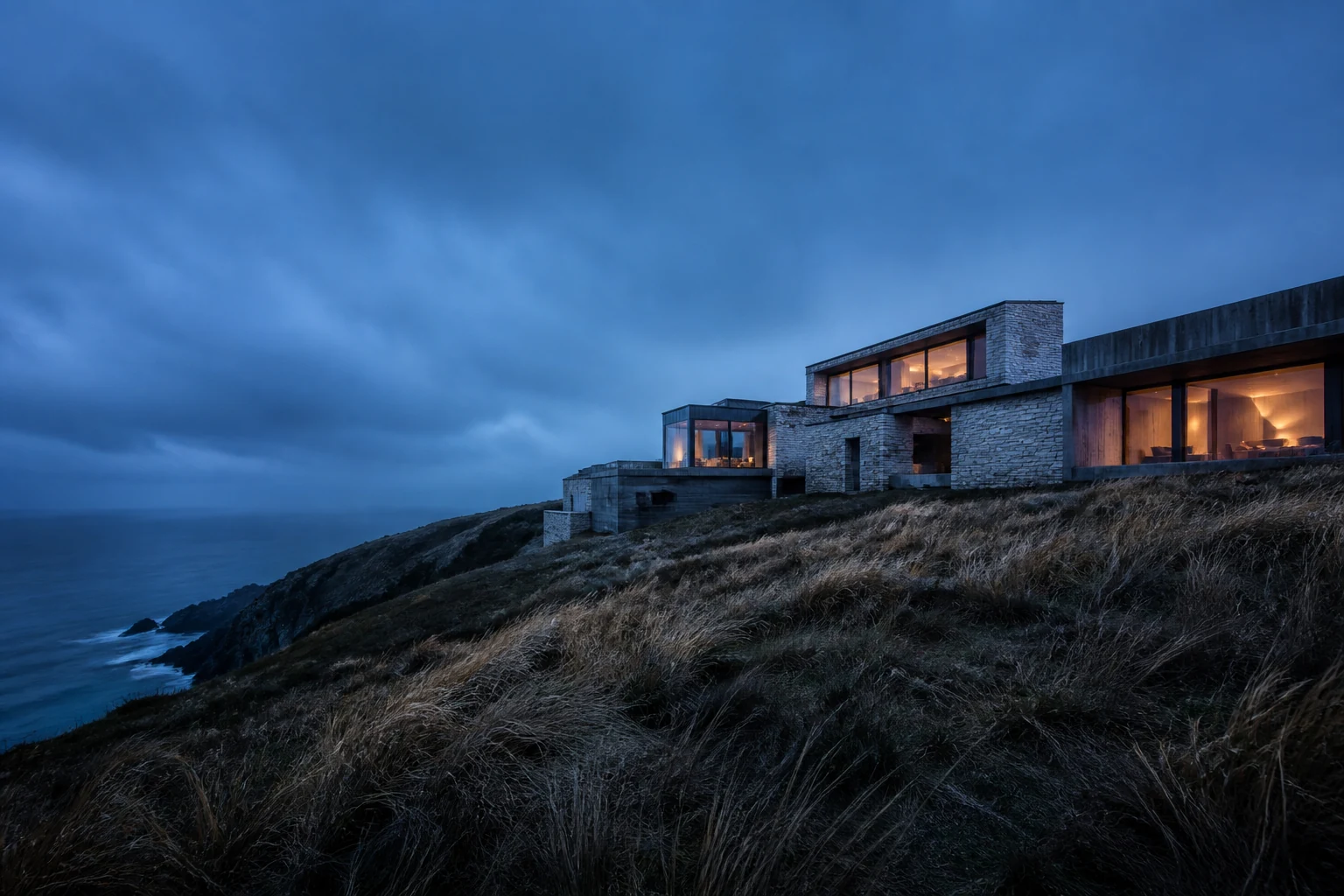 Cairn 17 stone residences overlooking a dark coastal headland at dusk