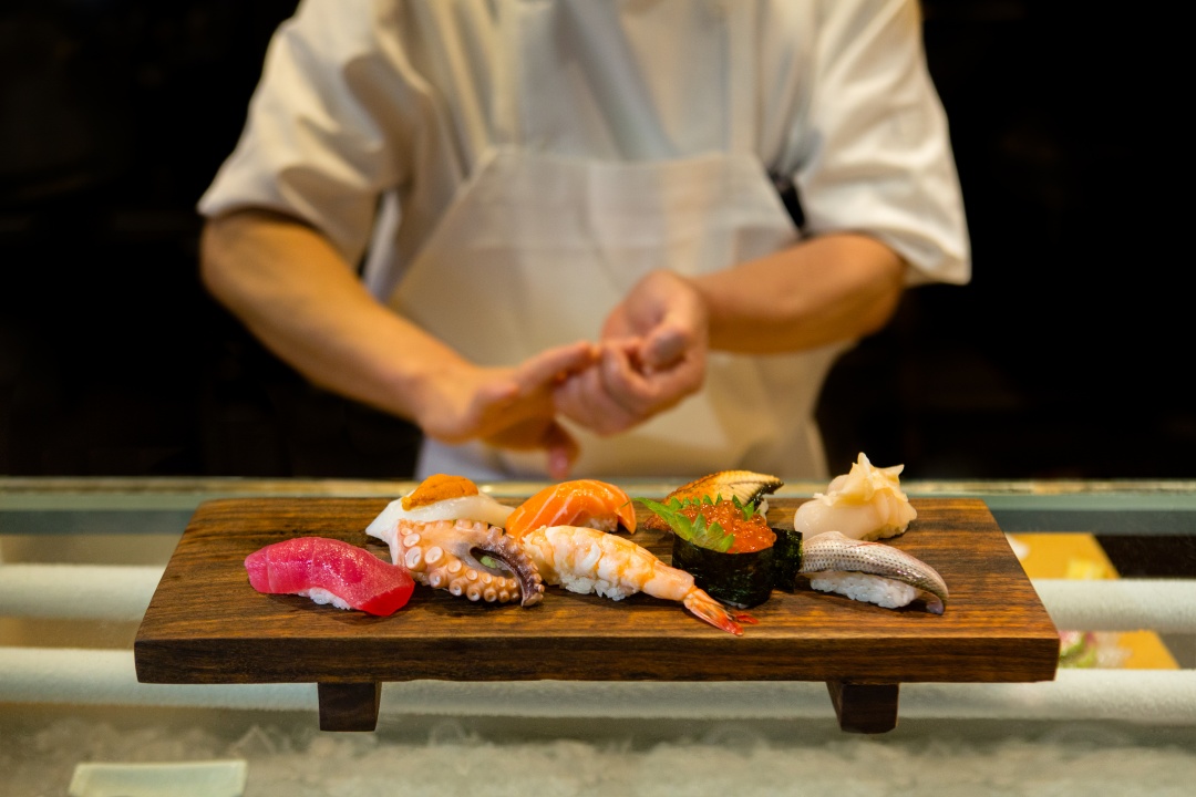 Sushi Den website showing a chef preparing nigiri at the counter